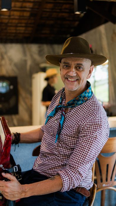 Carlos Magrão sorrindo, sentado com a gaita