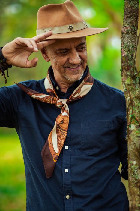 Carlos Magrão sorrindo, com a mão no chapéu